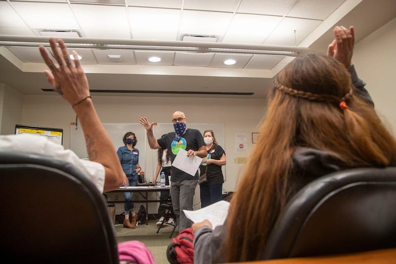 Casa Alterna co-founder Anton Flores-Maisonet speaks with immigrants and asylum seekers in a borrowed room at Atlanta's Hartsfield-Jackson International Airport, Thursday, Aug. 19, 2021. Volunteers with Casa Alterna, which was started during the COVID-19 pandemic, are stationed at the airport to assist immigrants and asylum seekers who are released from immigration detention in Georgia. Most immigrants and asylum seekers do not speak English. (Alyssa Pointer/Atlanta Journal Constitution)